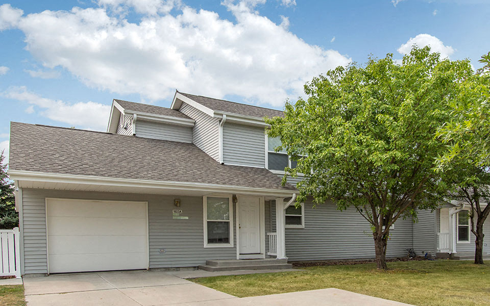 a gray house with a tree in front of it