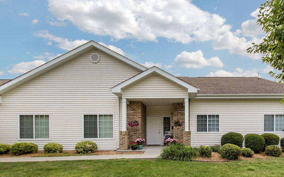 the front of a white house with a porch and a lawn