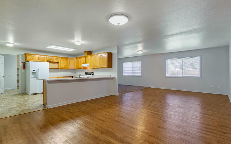 an empty living room and kitchen with a wood floor