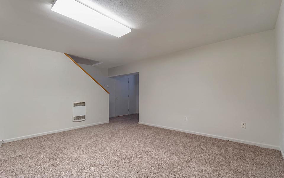 an empty living room with white walls and carpet
