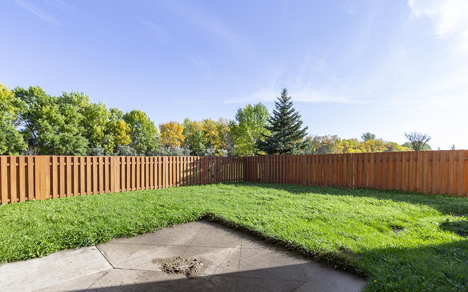 a backyard with a wooden fence and grass