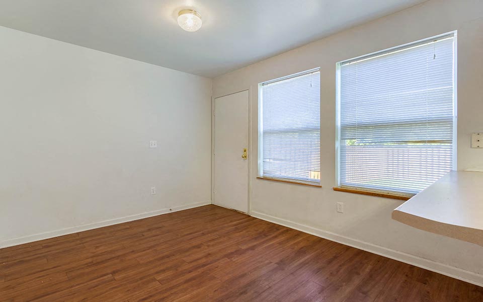 an empty room with a hard wood floor and two windows