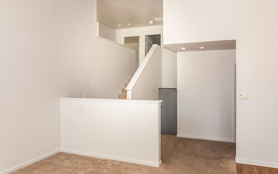 an empty room with a white wall and a staircase