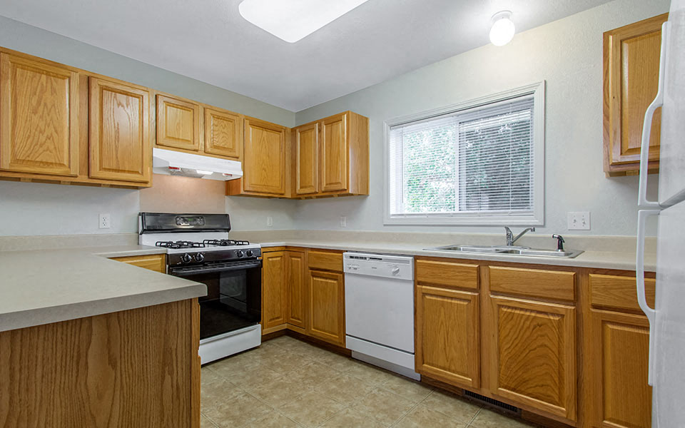 a kitchen with wooden cabinets and a stove and a window
