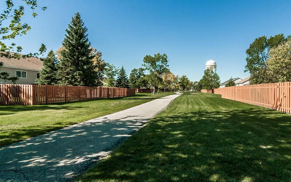 a sidewalk in the middle of a yard with a fence