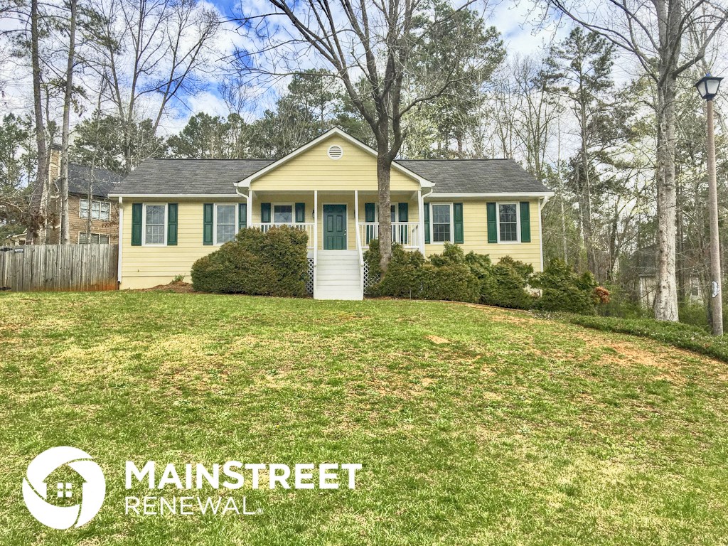 a yellow house with green shutters and a lawn