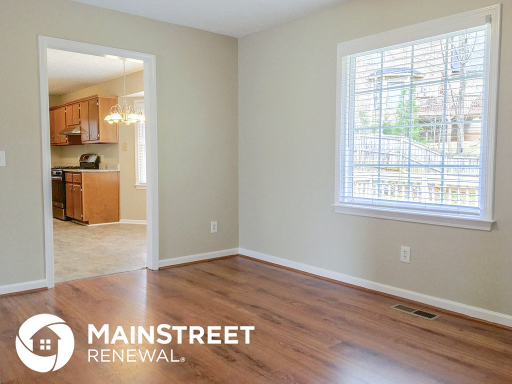 an empty living room with wood floors and a large window
