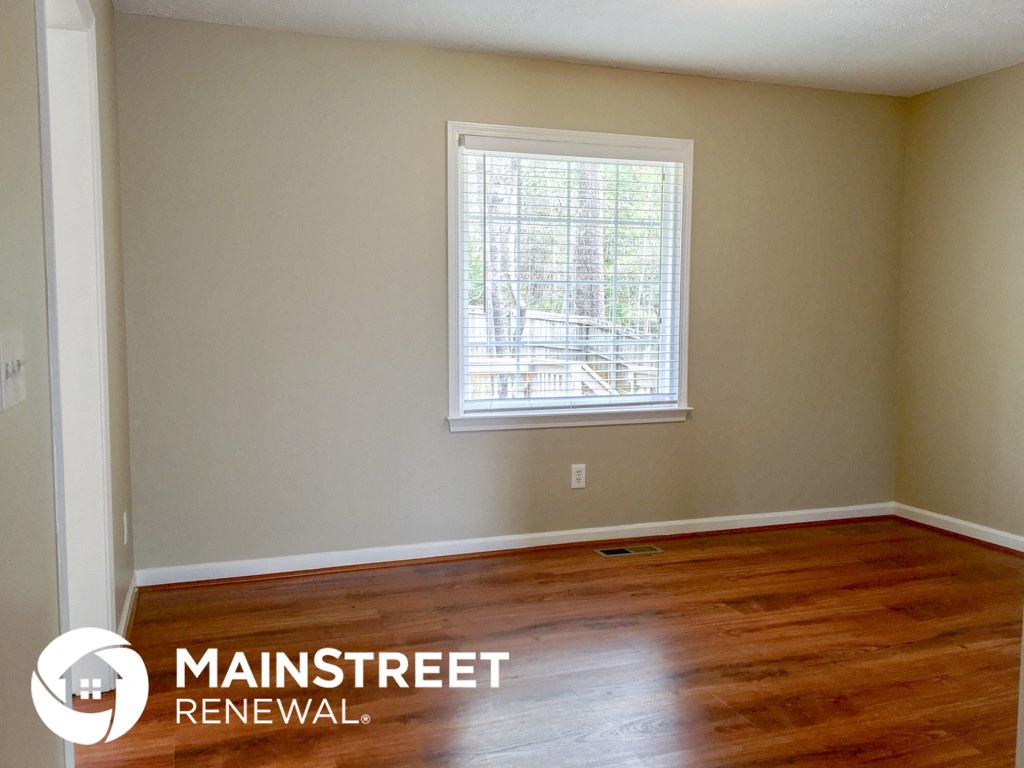 an empty room with a window and wooden floors