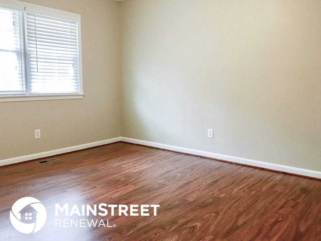 a room with wood floors and a window and white walls