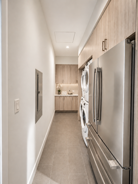A modern kitchen with a stainless steel refrigerator and a washing machine.