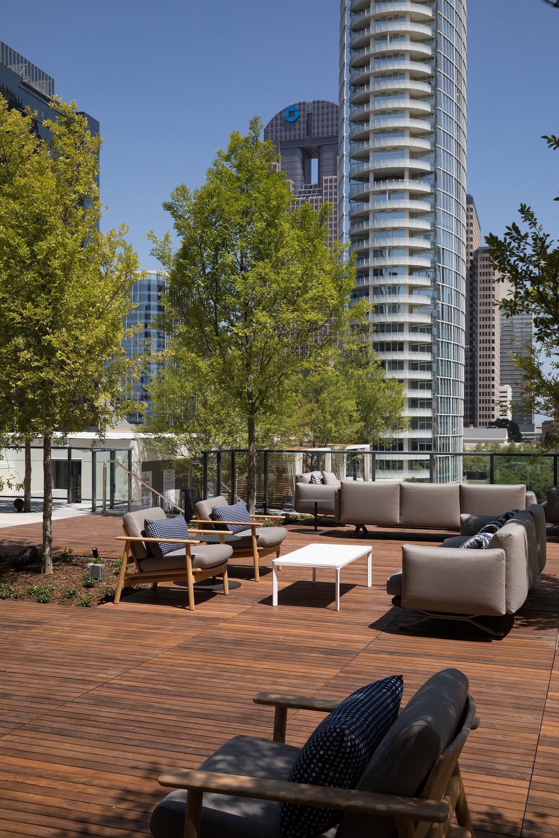 a rooftop deck with furniture and trees and skyscrapers