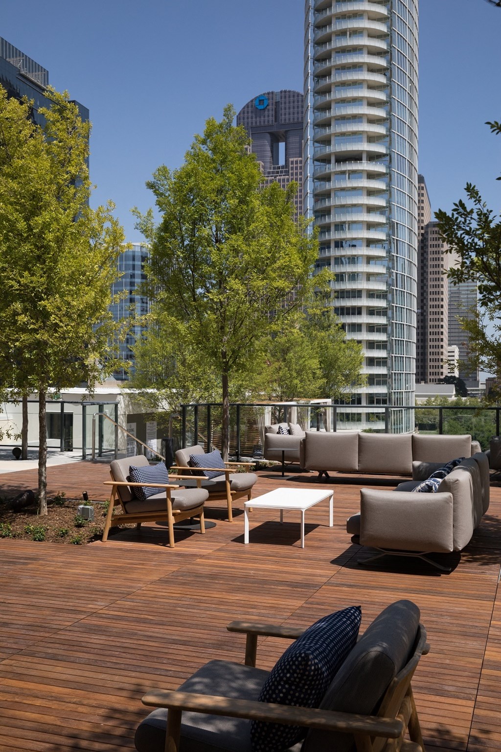 a rooftop deck with furniture and trees and skyscrapers in the background