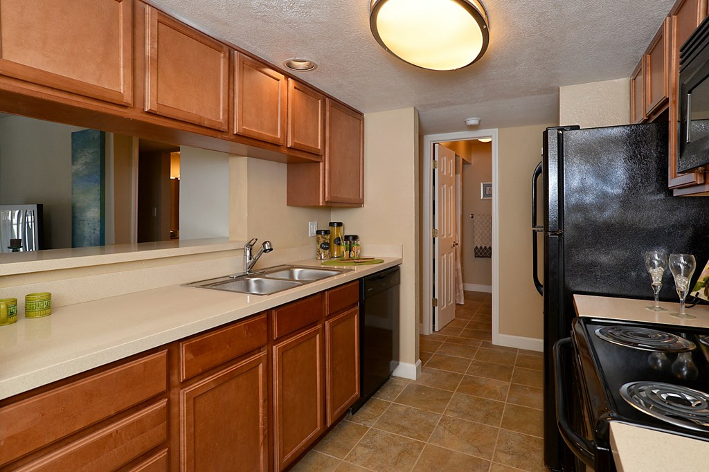 Kitchen with black appliances and wooden cabinets at Broadwater Apartments in St Petersburg, FL 33711