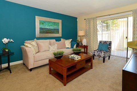 Living room with blue walls and a tan couch at Broadwater Apartments in St Petersburg, FL 33711