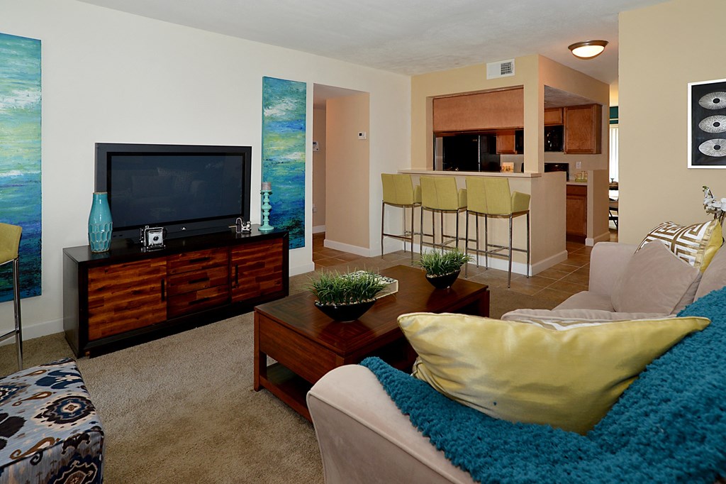 a living room with a television and a kitchen in the background at Broadwater Apartments in St Petersburg, FL 33711