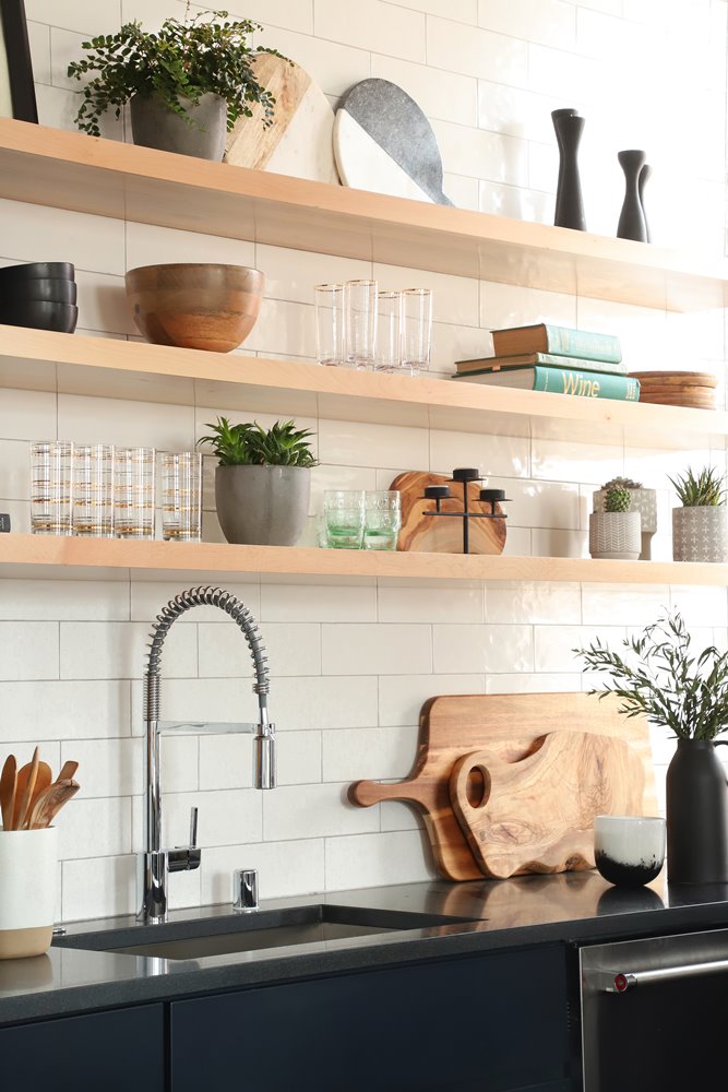 A kitchen with a black counter and a wooden cutting board.