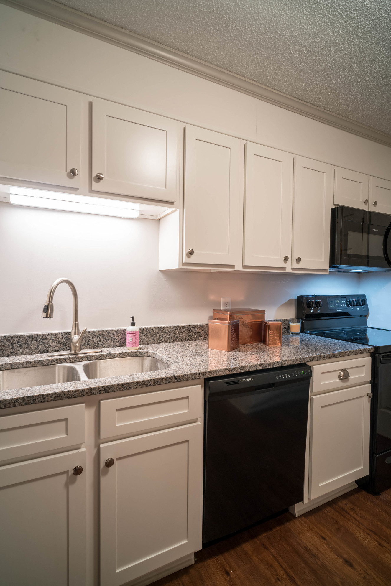 a kitchen with white cabinets and granite counter top and black appliances