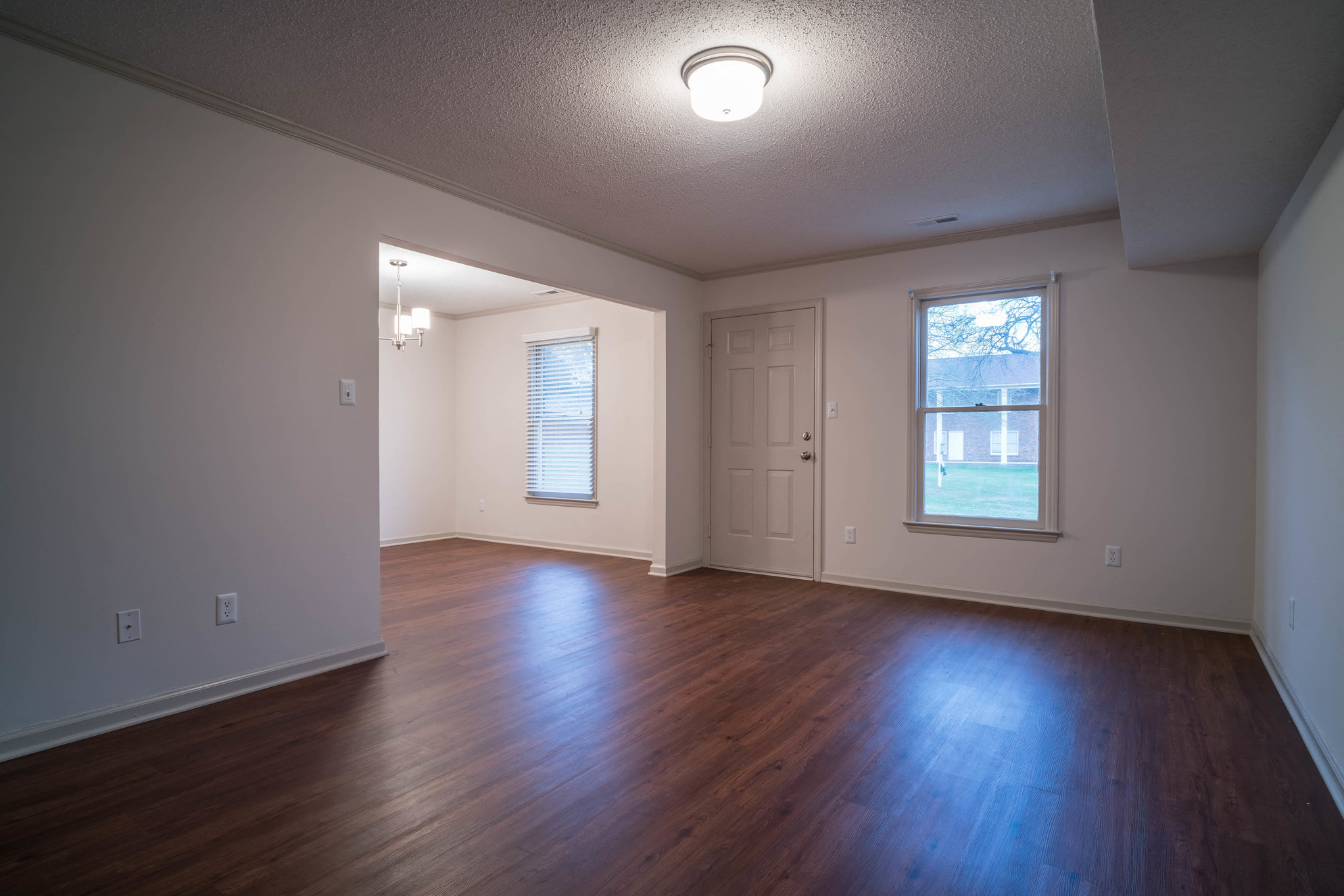 an empty living room with wood floors and a window