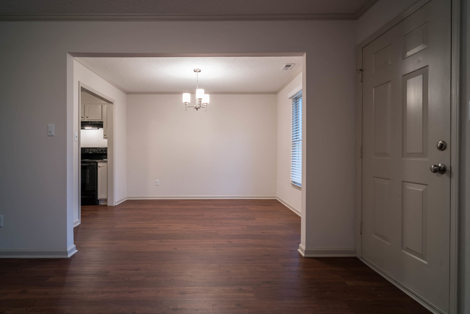 an empty living room with wooden floors and a white door