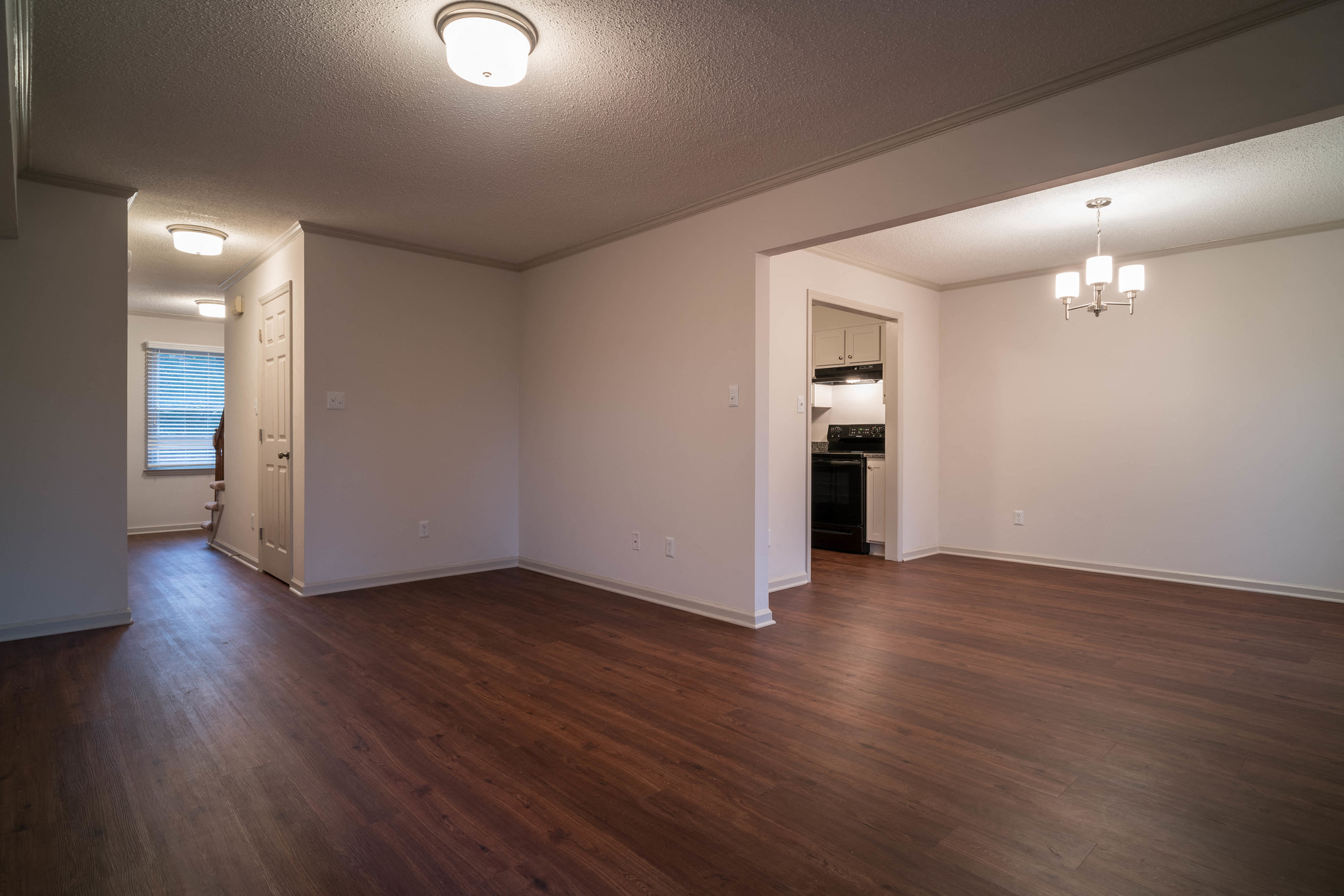 an empty living room with wood flooring and white walls