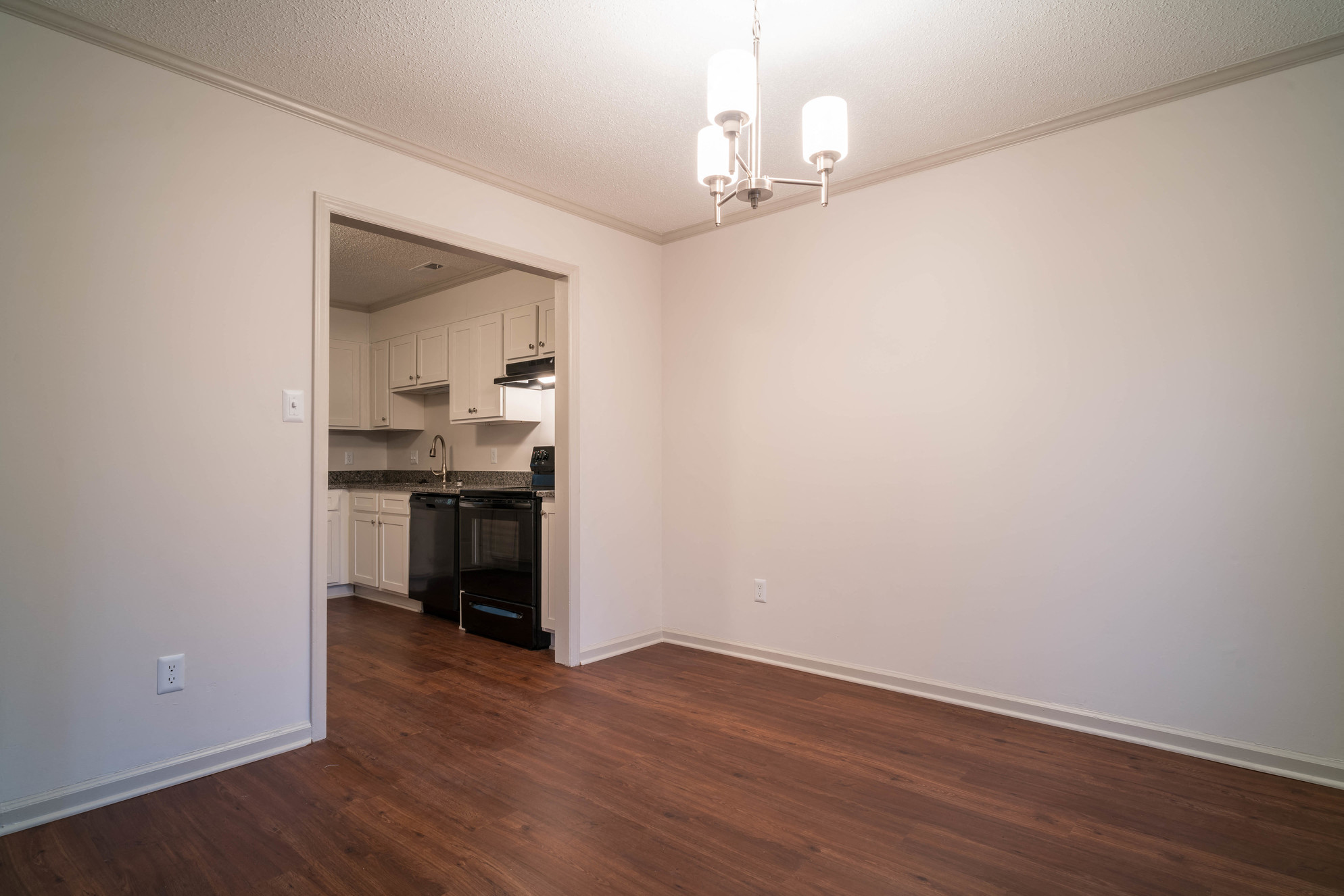 a living room with a hard wood floor and a doorway to a kitchen