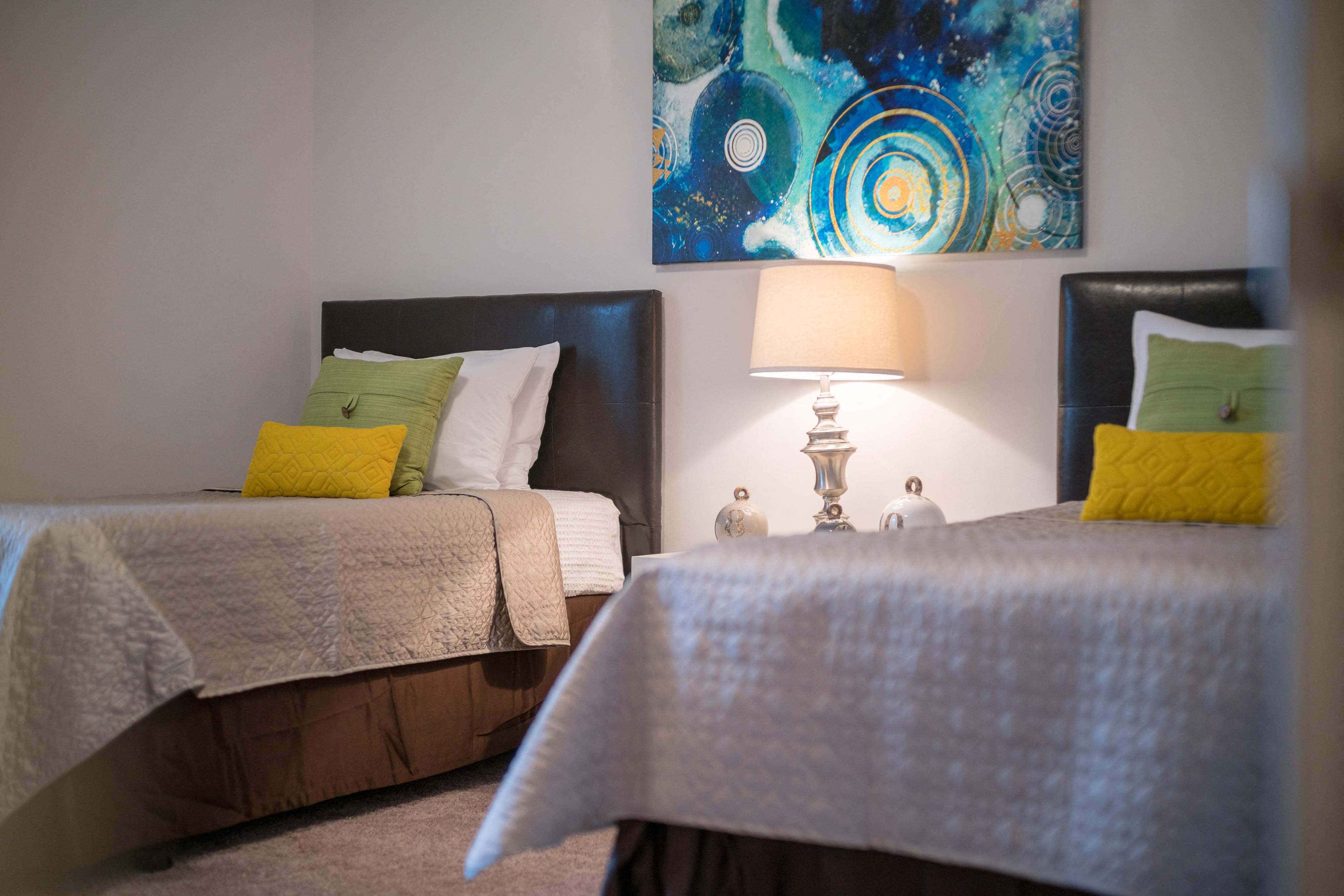 two beds in a room with a painting on the wall