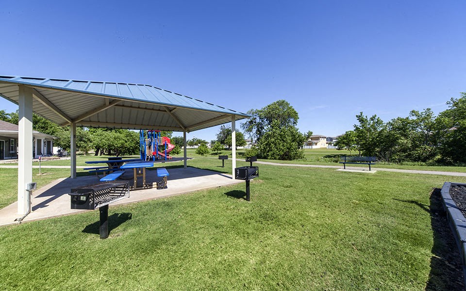 a picnic pavilion with a playground in a park