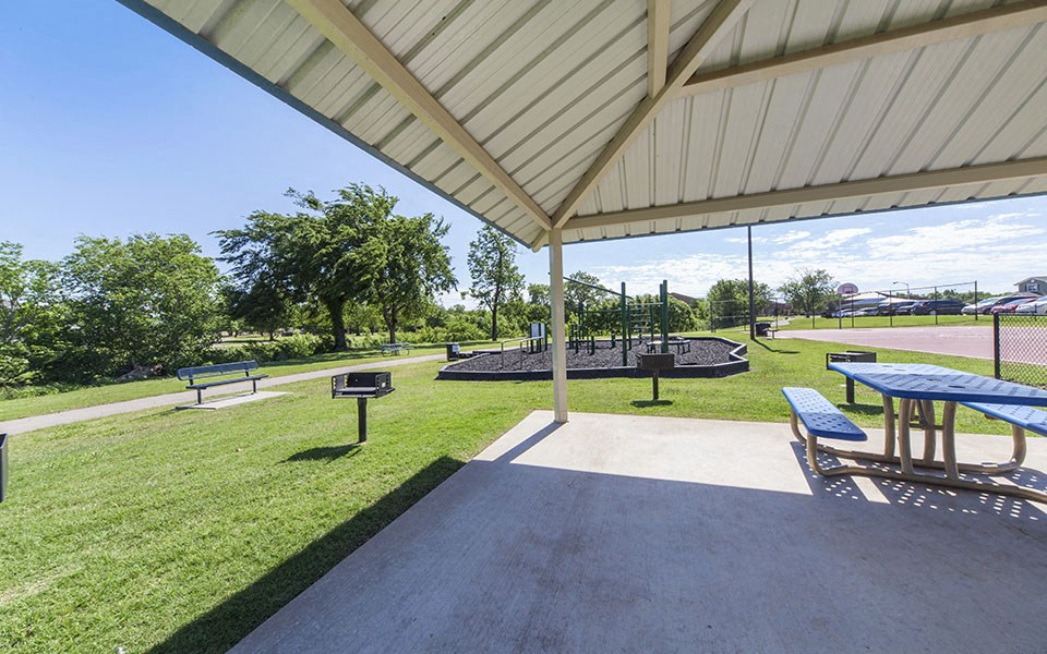 a picnic area with picnic tables and a grill in a park
