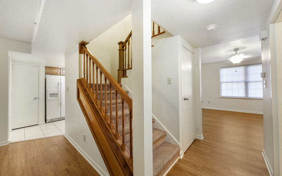 two pictures of a house with a staircase and a kitchen
