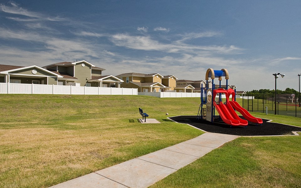 a playground in a park with houses in the background