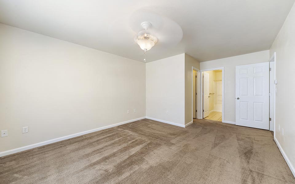 an empty living room with carpet and a white door