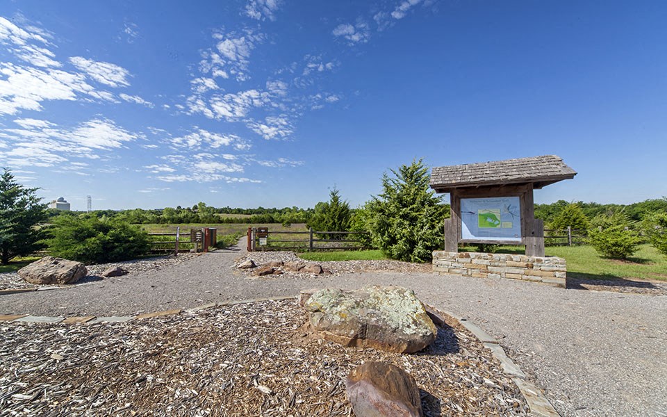 a park with a sign and trees and rocks