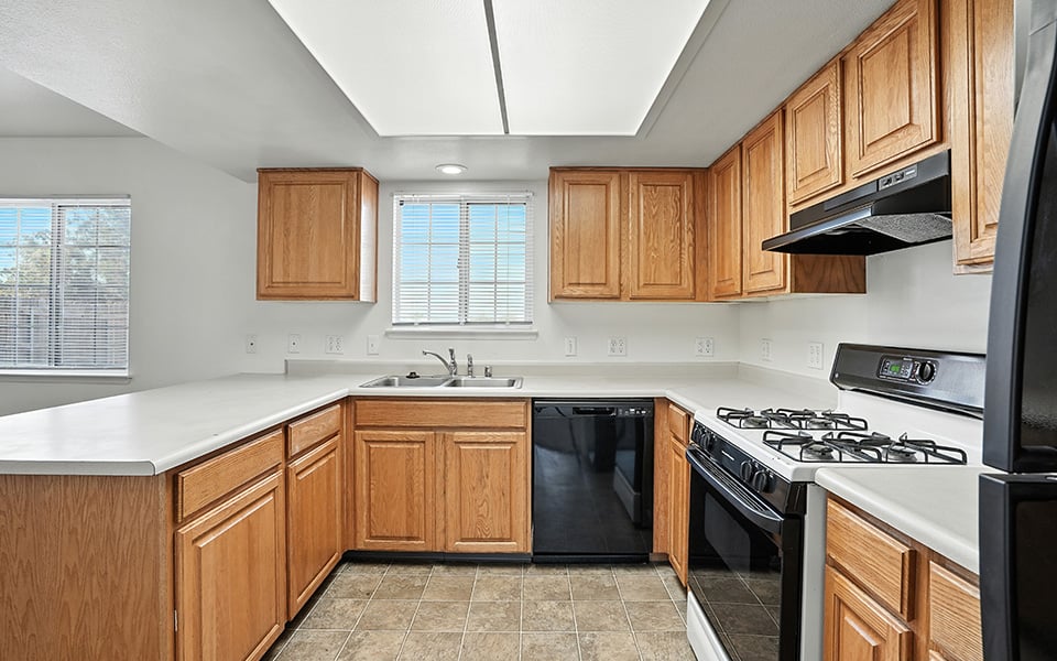 A kitchen with wooden cabinets and a black dishwasher.