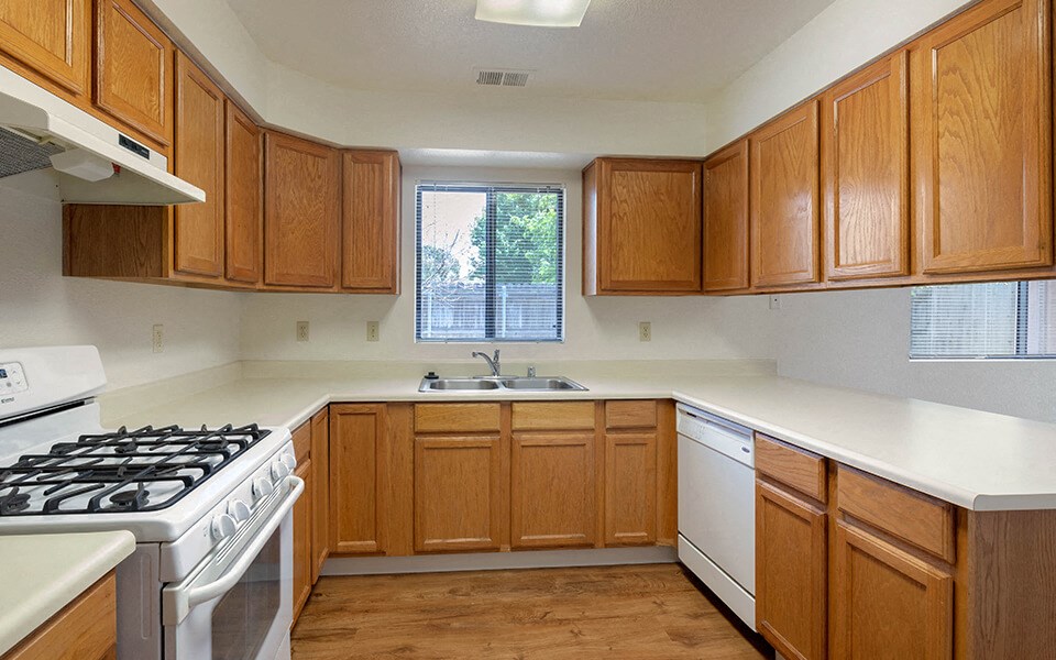 an empty kitchen with wooden cabinets and white appliances