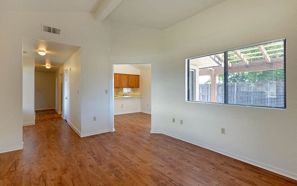an empty living room with a large window and wood floors