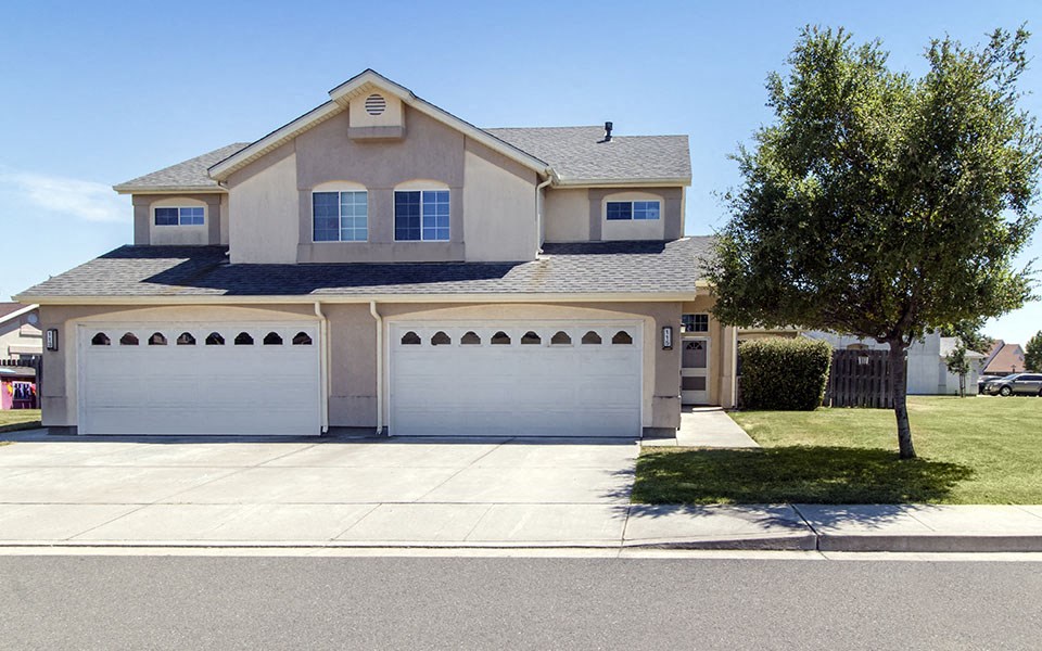a house with two garage doors in front of a driveway