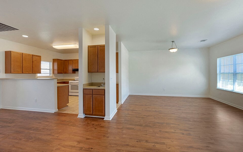 an empty living room and kitchen with wood flooring