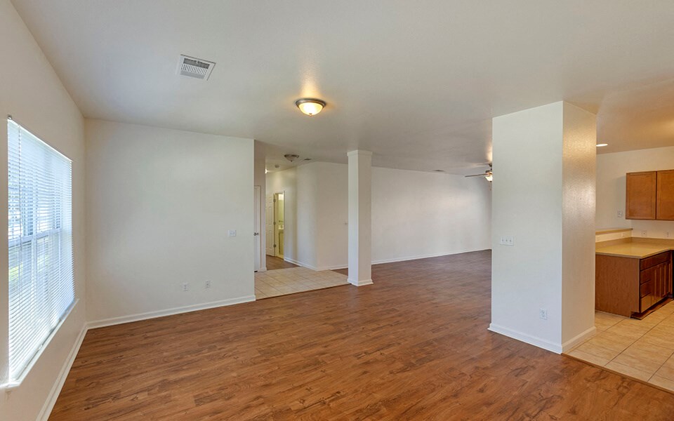 the living room and dining room of an empty home with wood flooring