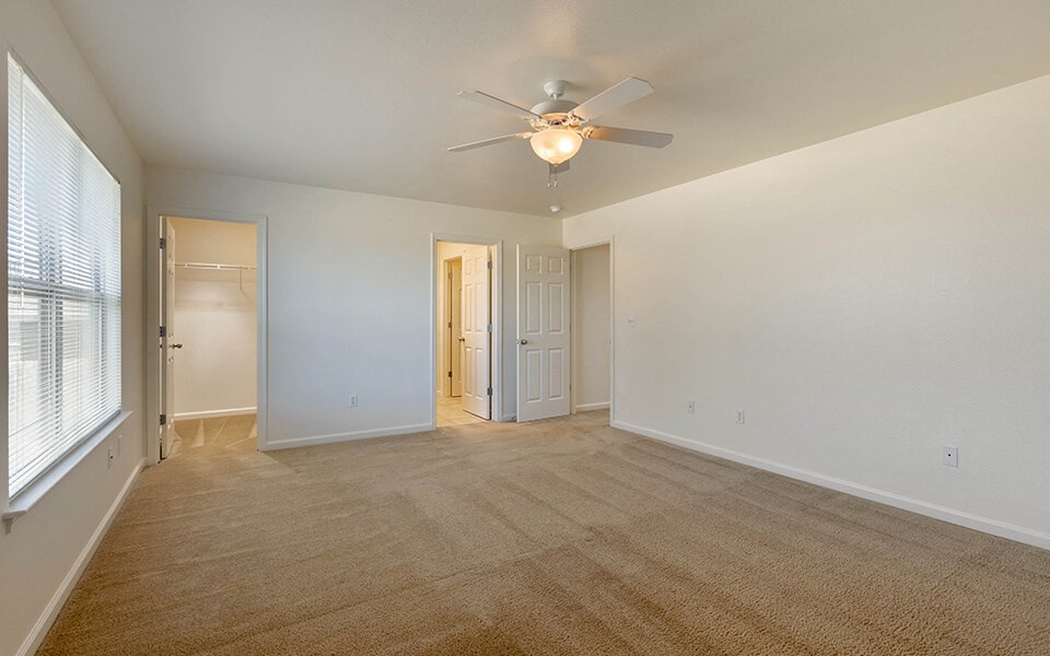 an empty living room with a ceiling fan and window