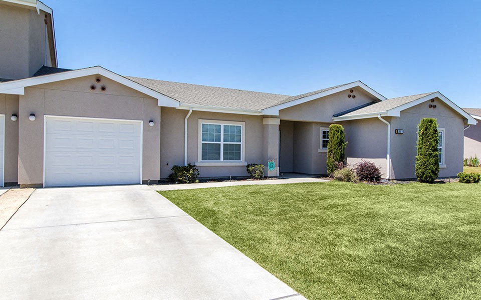 a beige house with a garage door and a lawn