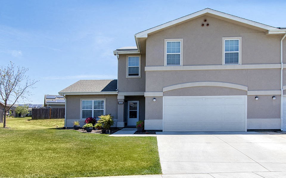 a beige house with a white garage door and a lawn
