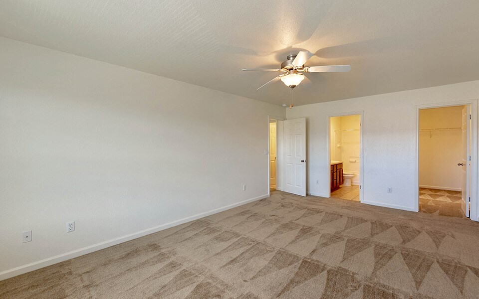 the living room of an empty house with a ceiling fan