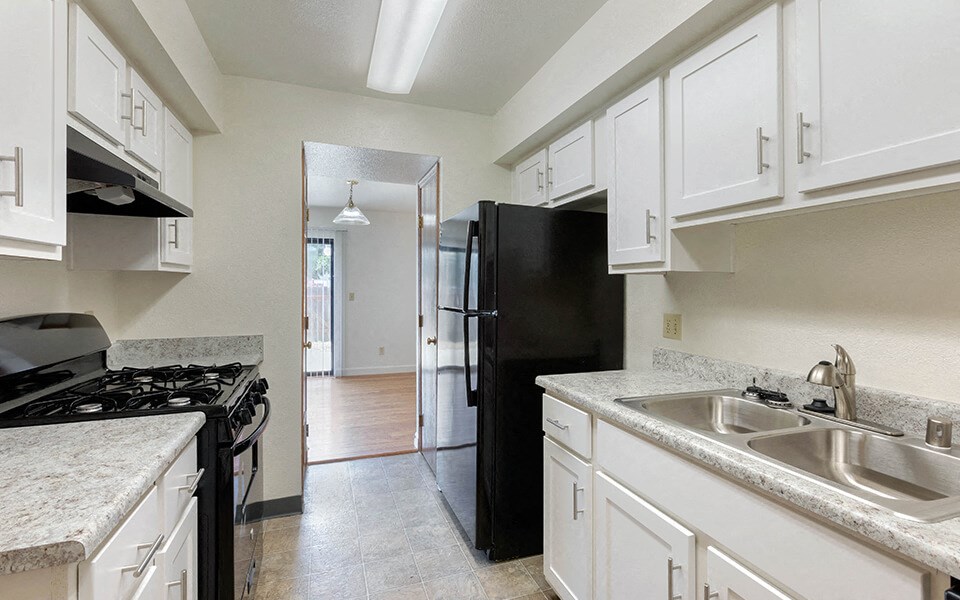 a kitchen with white cabinets and a black refrigerator