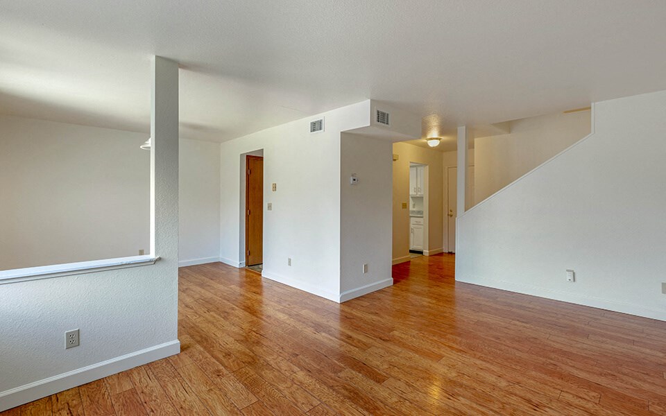 an empty living room with wood floors and white walls