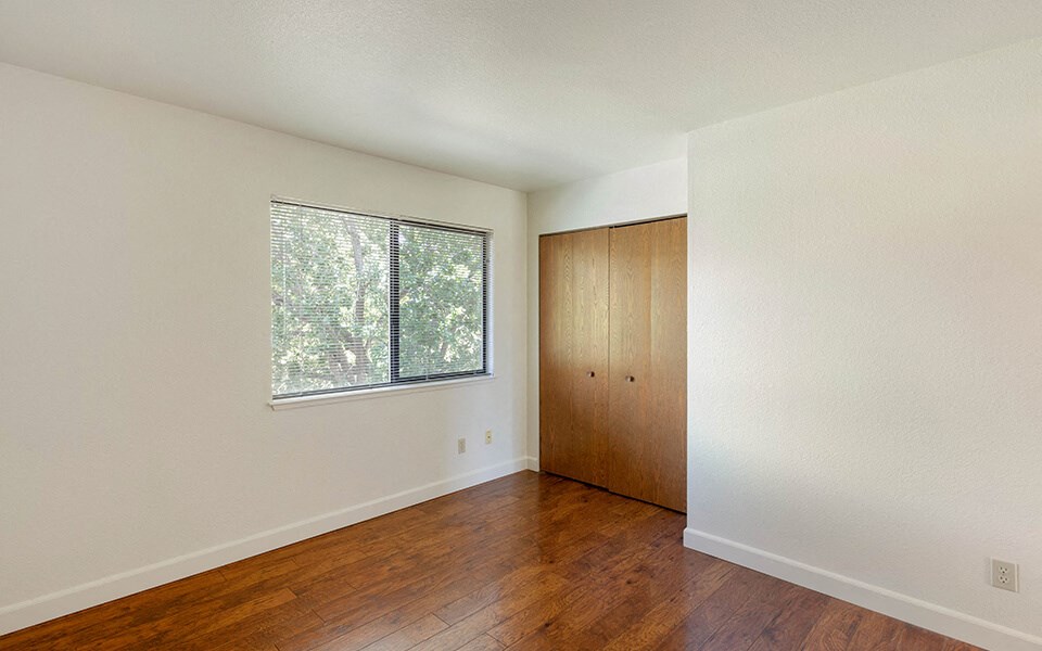 an empty living room with hard wood floors and a window