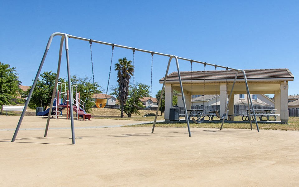 a swing set with a pavilion in a park
