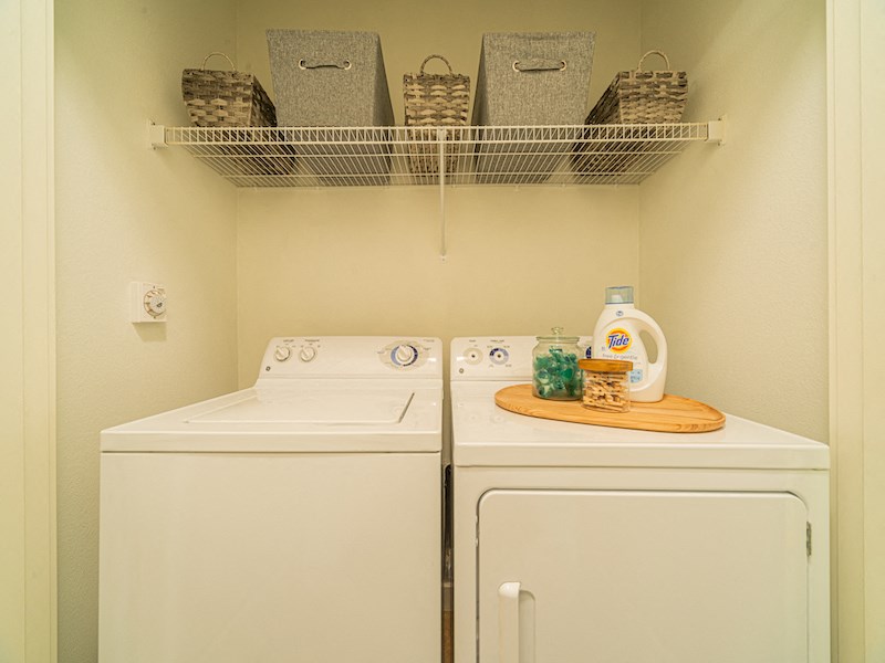 a washer and dryer in a laundry room with a shelf on the wall