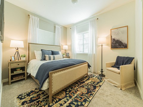 a bedroom with a bed and a chair and two windows