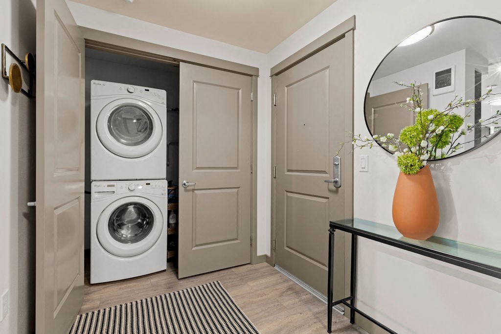 a washer and dryer in a hallway with a door to a laundry room