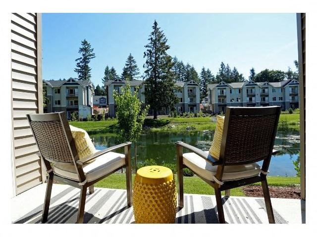 two chairs sitting on a porch overlooking a lake and houses